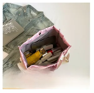 Interior view of large pink quilted tote bag showing tablet umbrella and makeup items