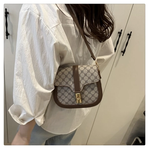 Detail of vintage canvas saddle bag with leather trim worn by a model in soft lighting