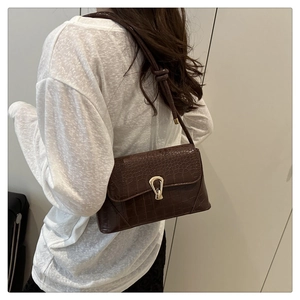 Detailed view of dark brown faux crocodile leather shoulder bag with gold horseshoe buckle