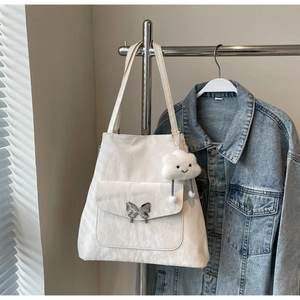 Detail of cream tote bag with silver butterfly buckle and cloud plush pendant