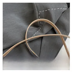 Detailed macro view of woven texture and premium leather strap stitching on beige handbag