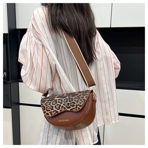 Detail of a brown saddle bag with leopard print flap and adjustable wide shoulder strap