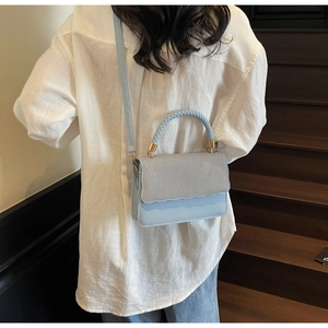 Détail du sac bandoulière bleu clair avec rabat tissé et design à bords ondulés