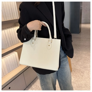 Detailed view of white faux leather tote bag with gold hardware and removable shoulder strap