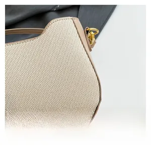 Detail of beige woven texture and light coffee leather trim on a stylish shoulder bag