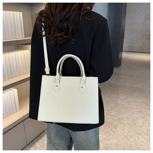 Minimalist white leather tote bag shown on model in a professional office setting