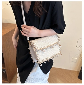 Detail of handwoven straw bag featuring delicate shell decorations and bead tassels