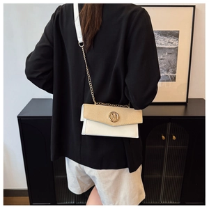 Détail d'un sac bandoulière en cuir tressé avec logo M doré et bandoulière en chaîne