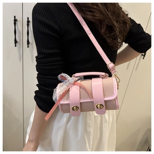 Detail of pink woven cylinder bag with gold twist lock and lace bow on a model