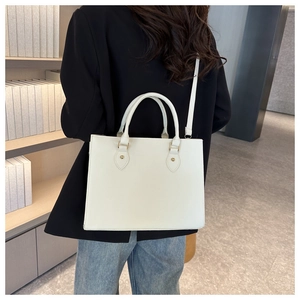 Detailed view of white minimalist tote bag with golden metal bead accents and strap