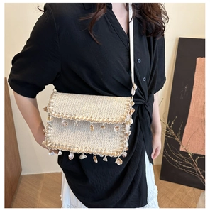 Detail of straw woven bag featuring elegant shell fringe tassels and a slim white strap
