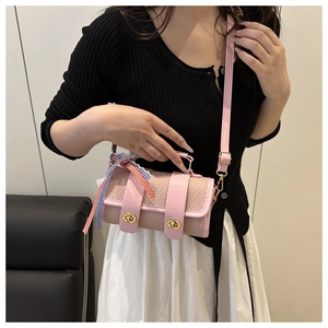 Détail du sac cylindrique rose tressé avec serrures métalliques et ruban au manche