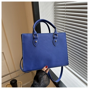 Close-up of blue business tote bag showing cross-grain texture and golden hardware