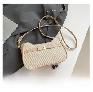 Detail view of beige woven handbag featuring a matching bow and gold buckle accessory