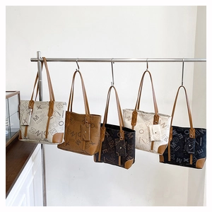Detail view of large tote bags with letter patterns in multiple colors and mini pouches