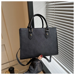 Detail of Saffiano leather texture on black tote bag with elegant gold metal hardware