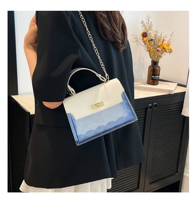 Detail of white and blue crossbody bag with gold twist lock and chain strap on a model
