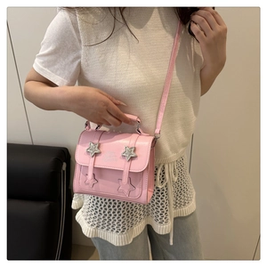Close-up of pink crossbody bag featuring silver star buckles and a stylish faux leather finish