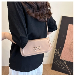 Detailed side view of a pink baguette bag with metallic bow clasp on a model