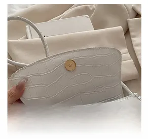 Dettaglio della borsa bianca in pelle PU a trama coccodrillo con chiusura magnetica dorata