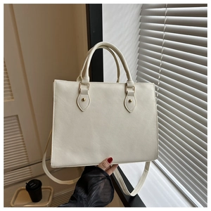 Detail view of the cream tote bag with cross-grain texture and golden hardware accents