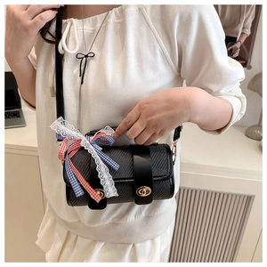 Détail du sac cylindre noir tressé avec fermoir doré et ruban en dentelle sur l'anse