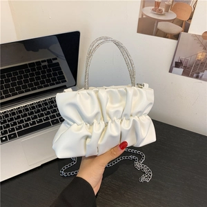 White pleated PU handbag with rhinestone handles and silver chain strap shown in lifestyle setting