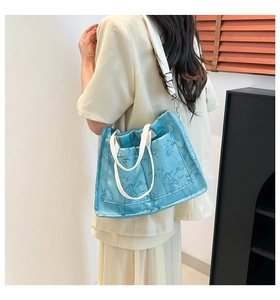 Detail of blue tote bag with bamboo leaf pattern and white fabric shoulder strap