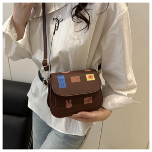Details von bunten Hasen- und Herz-Prints auf einer braunen Vintage Leder Satteltasche
