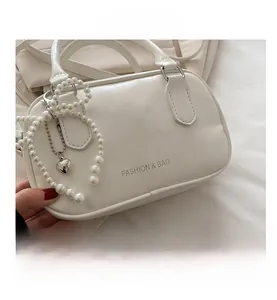 Detail of cream white leather pillow bag with pearl heart charm and fashion lettering