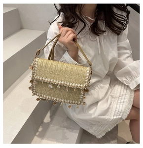 Detail of straw woven shoulder bag featuring bohemian shell and fringe tassel accents