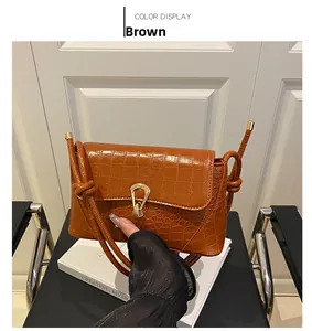 Close-up of brown faux crocodile leather bag with a golden ring buckle and knotted strap