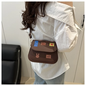 Detail of a brown crossbody bag featuring playful rabbit and heart stamp patches