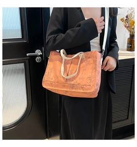 Detail of orange tote bag with bamboo leaf pattern and white shoulder strap shown on model