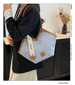 Detail of blue canvas tote bag with brown leather trim and wide graphic shoulder strap