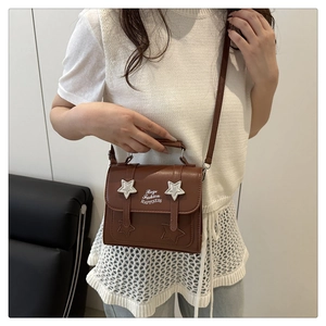Detail view of brown Maillard style crossbody bag featuring white star charms and shoulder strap