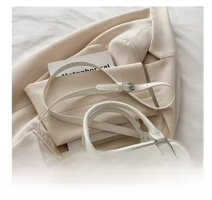 Close-up of white leather bowling bag with elegant pearl charm and adjustable strap