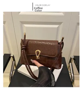 Detail shot of coffee brown crocodile pattern bag with U-shaped gold lock and long strap