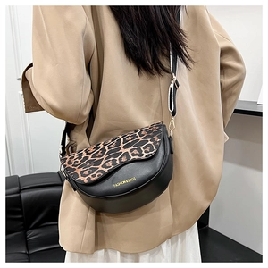 Detail of adjustable black strap and gold metal hardware on leopard print saddle bag