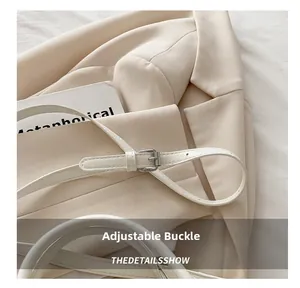 Detailed macro view of adjustable silver metal buckle on white leather shoulder bag strap