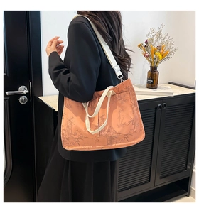 Side view of large orange floral tote bag with black bamboo pattern on a female model