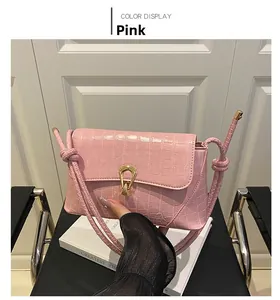 Detailed view of pink crocodile-embossed PU leather bag with gold buckle and knotted strap