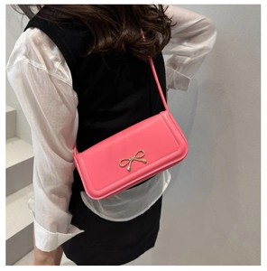 Detailed shot of pink bow shoulder bag with golden metallic buckle and smooth PU leather