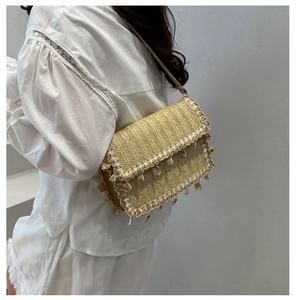 Detail of straw bag with scalloped lace edges and natural seashell charms for summer