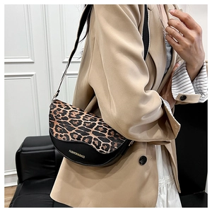 Detail of retro saddle bag with leopard print flap and gold FASHION & BAGS logo text