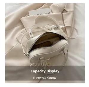 Interior view showing the large capacity of this cream Boston bag with pearl charm