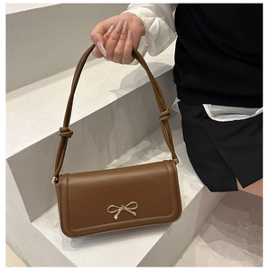 Brown PU leather crossbody bag featuring a golden bow buckle and knotted shoulder strap