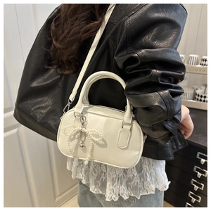 Detail of white mini pillow bag with beaded bow charm and heart pendant on PU leather