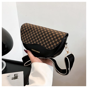 Close-up of saddle bag featuring brown logo pattern, black leather trim and gold buckle