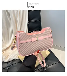 Detail of pink shoulder bag with bow accent and fine twill texture held by hand